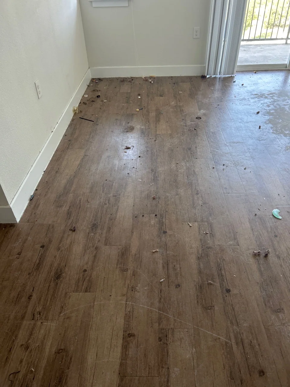Before cleaning: already-empty Swept Up Moving job living area with floor debris; photographed from a different angle than the after view.
