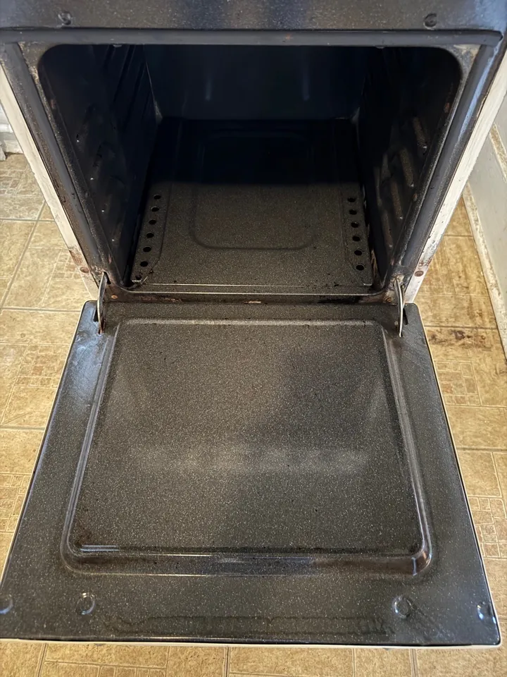 The same oven interior cleaned back to bare metal after a move-out clean