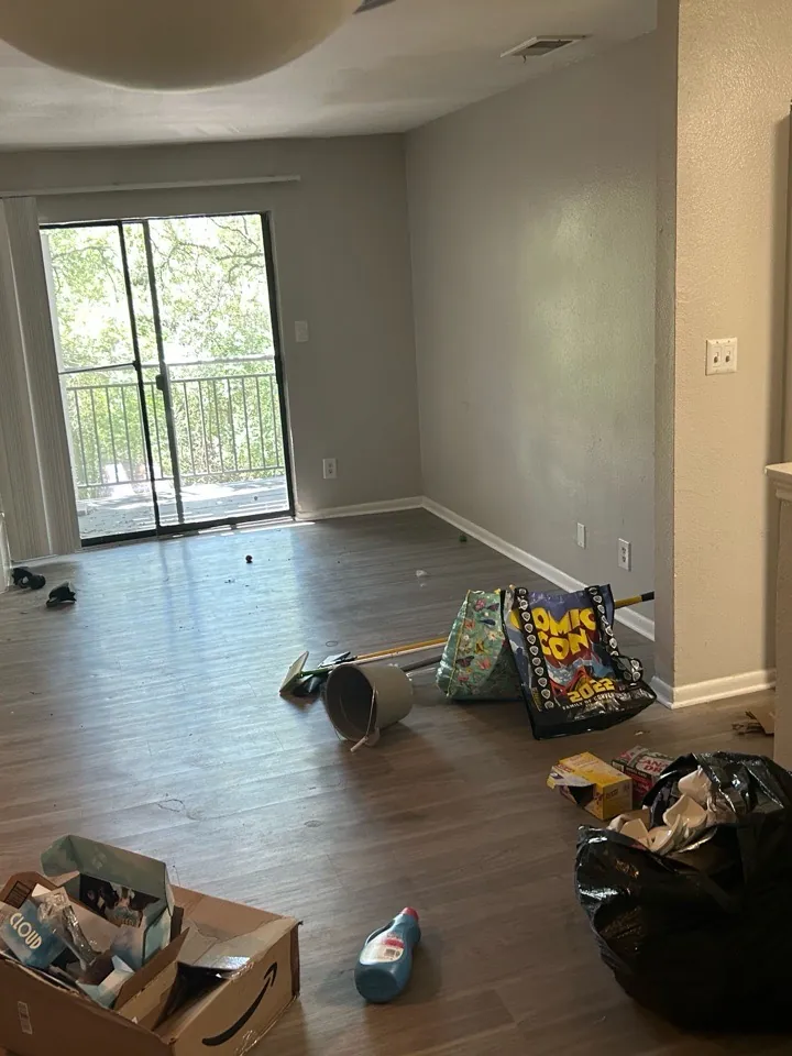 Apartment living room with belongings and debris left behind before a move-out clean